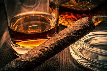 Decanter of whiskey and a glass with cuban cigar on a wooden table
