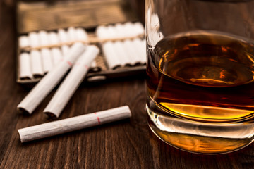 Glass of whiskey and cigarettes with a cigarette case on a wooden table