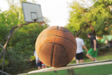 Basketball ball on a bench with defocused players in the background.