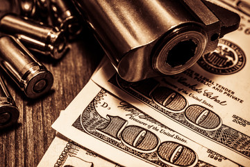 Barrel of a revolver with cartridges and money on the wooden table - obrazy, fototapety, plakaty