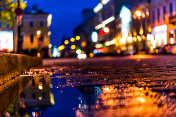 The bright lights of the evening city after rain, street with cars