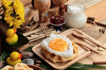 Sweet waffles and fresh milk with jam and egg heart.