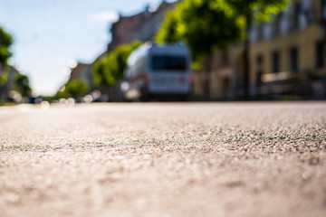 City on a sunny day, a quiet city street on which the car traveling. Close up view from the level of the asphalt