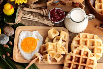 Sweet waffles and fresh milk with jam and egg heart.