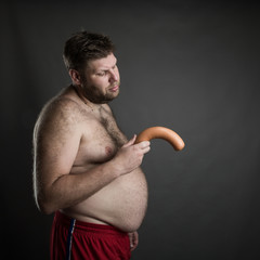 Sad man looks at the sausage in his hand