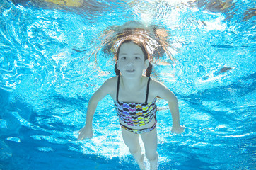 Obraz na płótnie Canvas Child swims in pool underwater, happy active girl has fun in water 