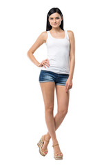 Full length portrait of a brunette woman who is in a white tank top and blue denim shorts. isolated.