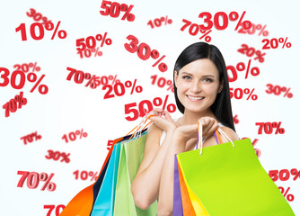 A happy young girl with the colourful shopping bags from the fancy shops. Discount signs are flying...
