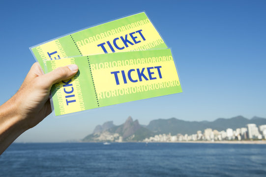 Hand Holding Pair Of Brazil Tickets In Front Of Sea View Ipanema Beach Rio De Janeiro With Two Brothers Dois Irmaos Mountain 