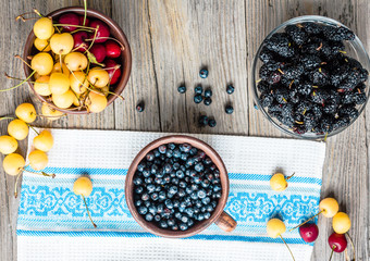Fresh blueberries, cherries and mulberries on a gray wooden back