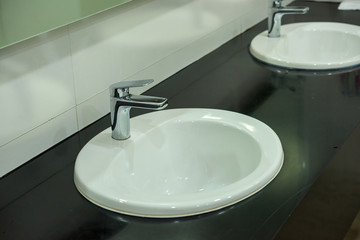 white basins in bathroom interior with granitic tiles.