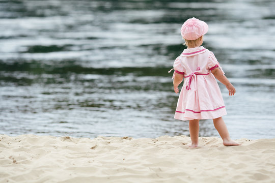 little girl standing on the coast of river
