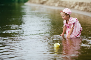 girl plays with paper boats in river