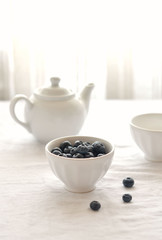 blueberries in white bowl on table with white tablecloth