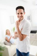 Fototapeta premium portrait of handsome young man at home with his girlfriend in background
