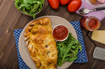 Calzone pizza stuffed with cheese and prosciutto
