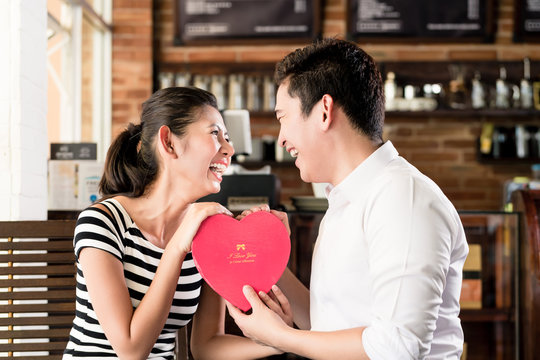 Asian couple having date in coffee shop with red heart