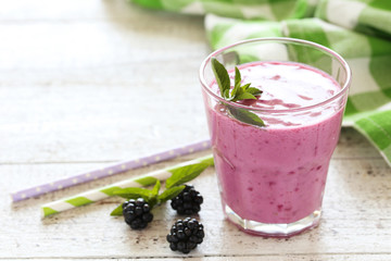 Blackberry smoothie in the glass on white wooden background