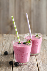 Blackberry smoothie in the glasses on grey wooden background