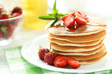Tasty pancakes with strawberry on white wooden background