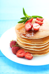Tasty pancakes with strawberry on blue wooden background