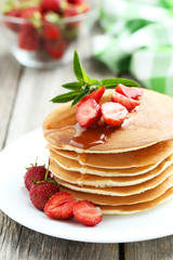 Tasty pancakes with strawberry on grey wooden background
