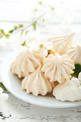 French meringue cookies on plate on white wooden background