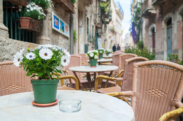Vase with white daisies on the table of a restaurant along the alleys in Ortigia, the old Syracuse