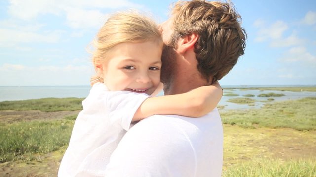Portrait of cute little girl giving kiss to daddy