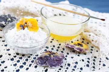 Making candied violet flowers with egg whites and sugar, on color wooden background