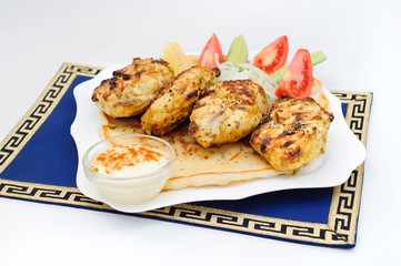 Greek grill meatball on pita with tomato and cucumbers.