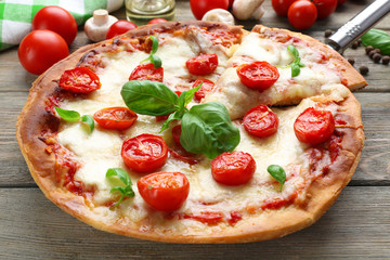 Delicious pizza with cheese and cherry tomatoes on wooden table, closeup