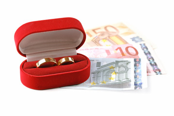 Wedding rings in box on banknotes, isolated on white background. Marriage of convenience