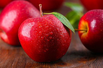 Red apples with droplets on wooden table, closeup