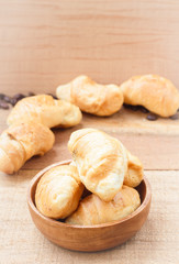 Croissants on wooden bowl, wooden table background