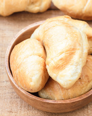 Croissants on wooden bowl, wooden table background