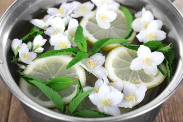 Cold refreshing summer drink with mint and slices of lemon in pan close up