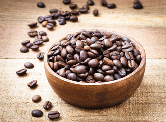 Coffee beans in wooden bowl on wooden background