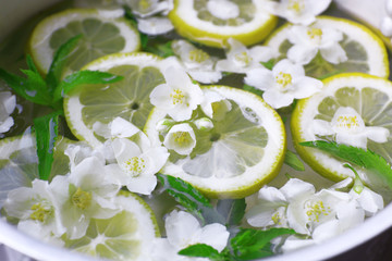 Obraz na płótnie Canvas Cold refreshing summer drink with mint and slices of lemon in pan close up