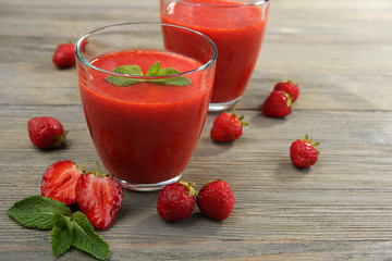 Glasses of strawberry smoothie with berries on wooden table close up