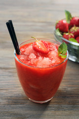Glass of strawberry smoothie with berries on table close up
