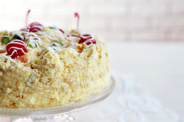 Butter cake with cherries on stand, on light background