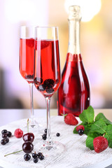 Glass of champagne with berries on light blurred background