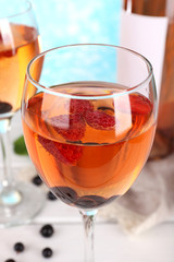Glasses of wine with berries on light blurred background