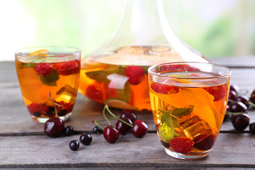 Punch with berries in glassware on wooden table on light blurred background