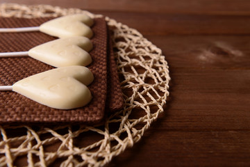Chocolate heart shaped candies on sticks on brown napkin, closeup