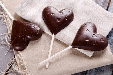 Chocolate heart shaped candies on sticks on sackcloth, closeup