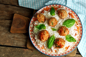 Meat balls in tomato sauce with boiled rice and lentil, wooden spoon on wooden background