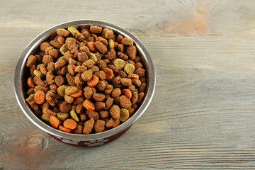 Dog food in bowl on wooden table