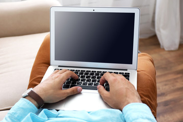 Man working with laptop on sofa in room